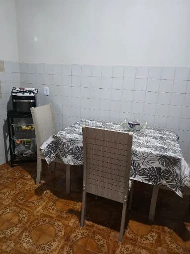 Mesa de refeições posta com toalha estampada e cadeiras estofadas, na copa da casa