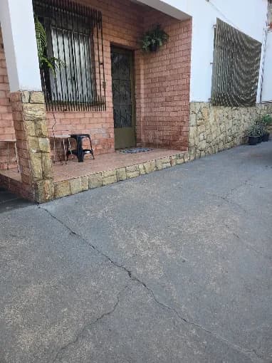 Fachada da casa do Lar de Idosos Vovó Nice, com varanda de tijolinho e plantas na entrada